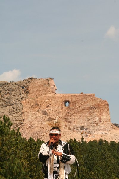 Trip (232).JPG - A native American in front of the Crazy Horse Memorial.  The sculpture's final dimensions are planned to be 641 feet wide and 563 feet high. The head of Crazy Horse will be 87 feet high; by comparison, the heads of the four U.S. Presidents at Mount Rushmore are each 60 feet high.  The monument has been in progress since 1948 and is far from completion.